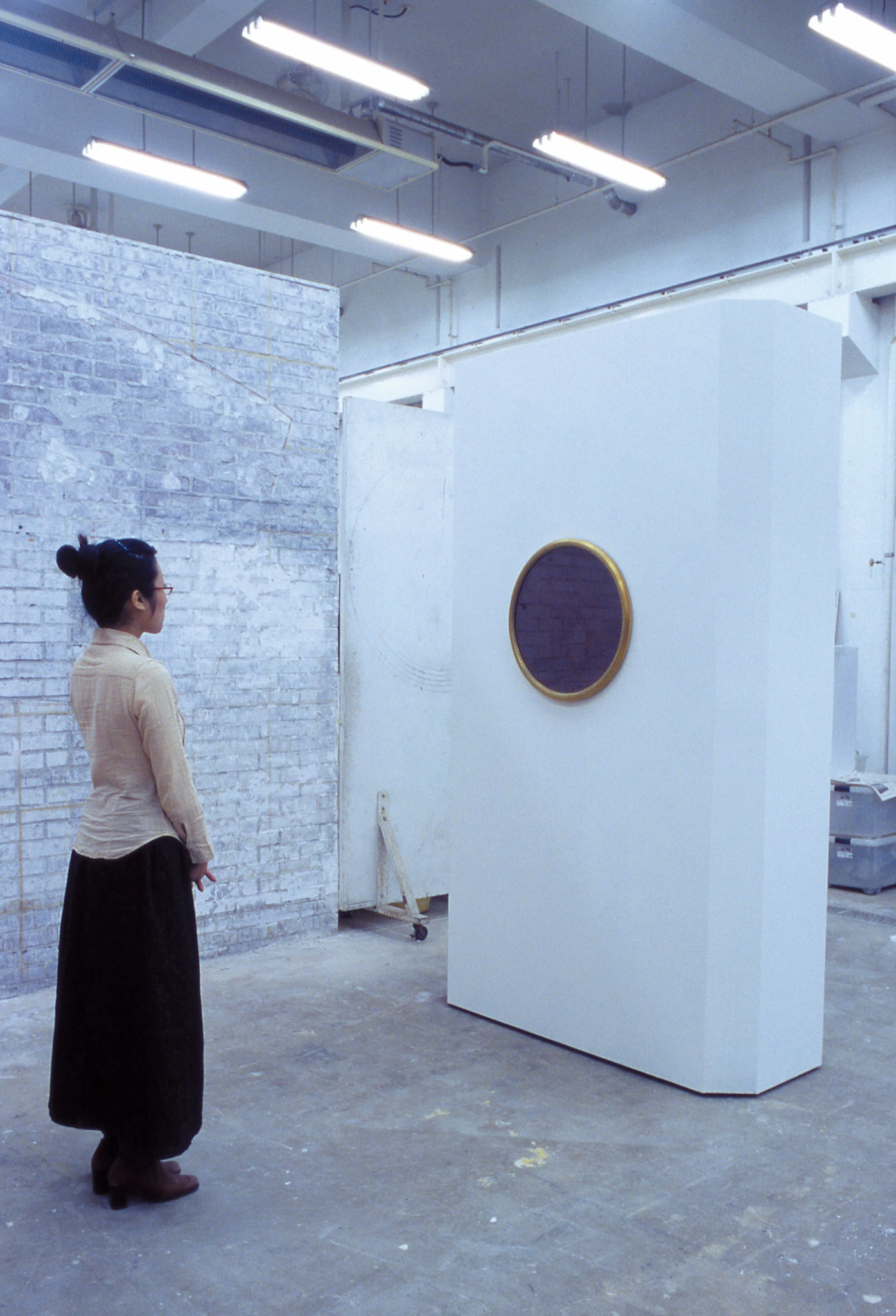 Viewer standing before the circular framed mirror