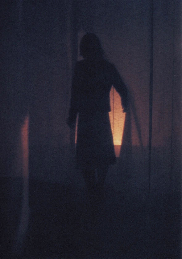 A figure emerging within the dark curtain space
