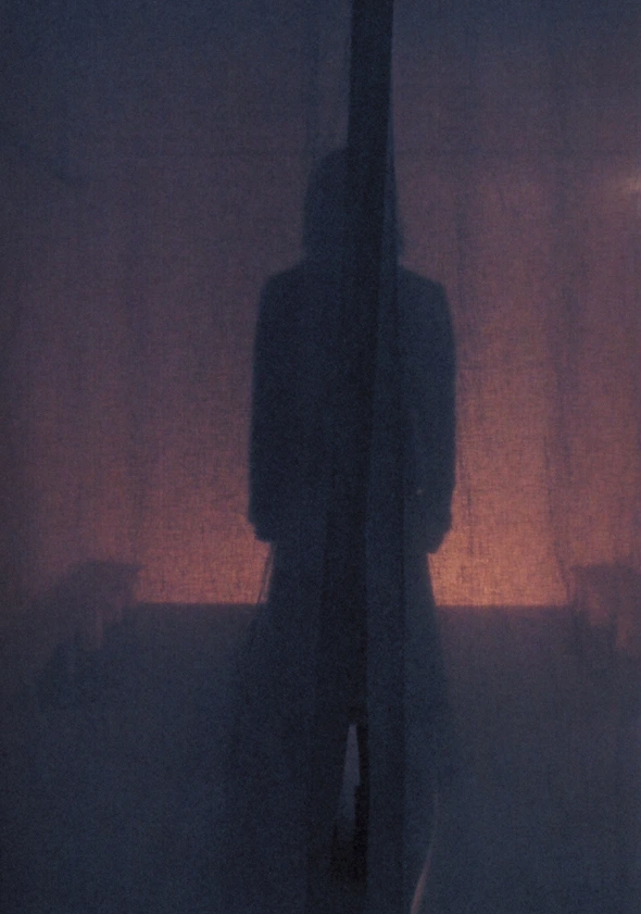 Silhouette within the curtain before the backlit space