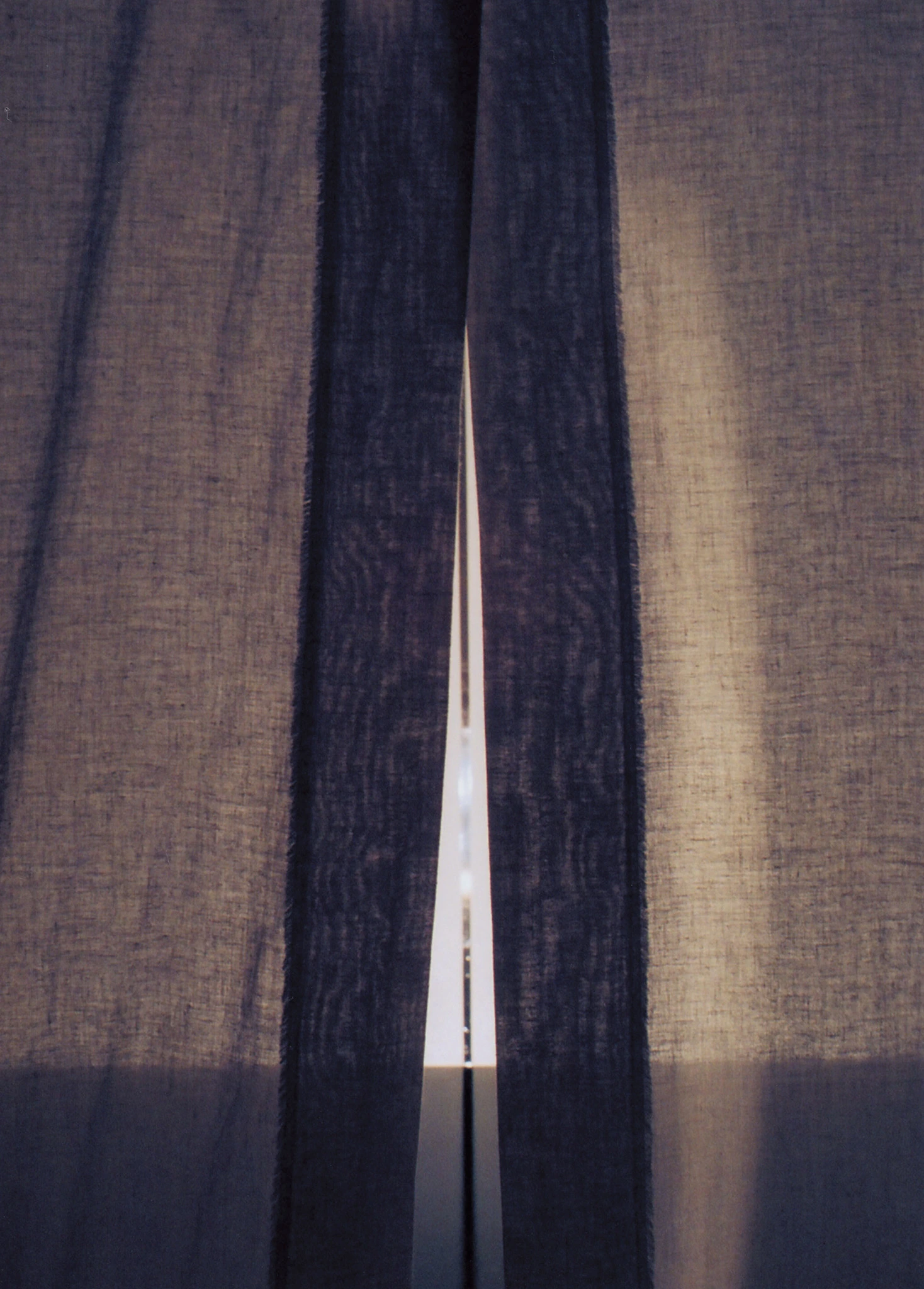 Close view of the slit between the curtain panels and the light beyond