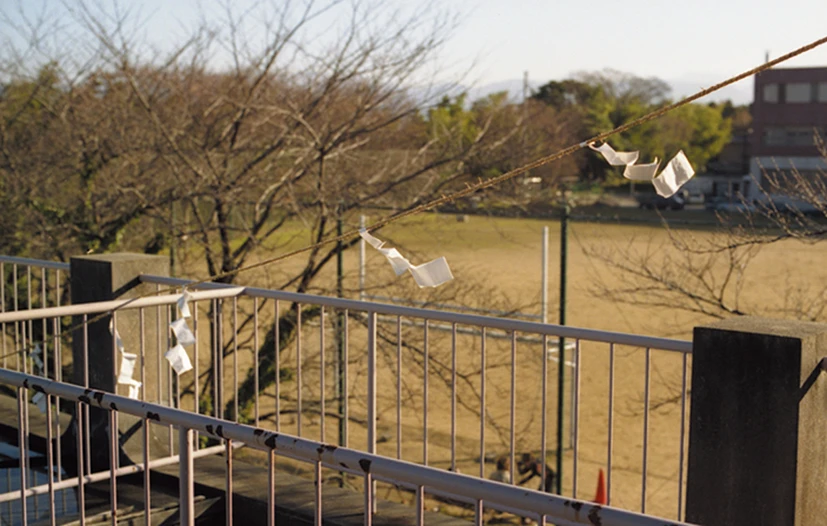 Paper gohei suspended above a railing and open ground