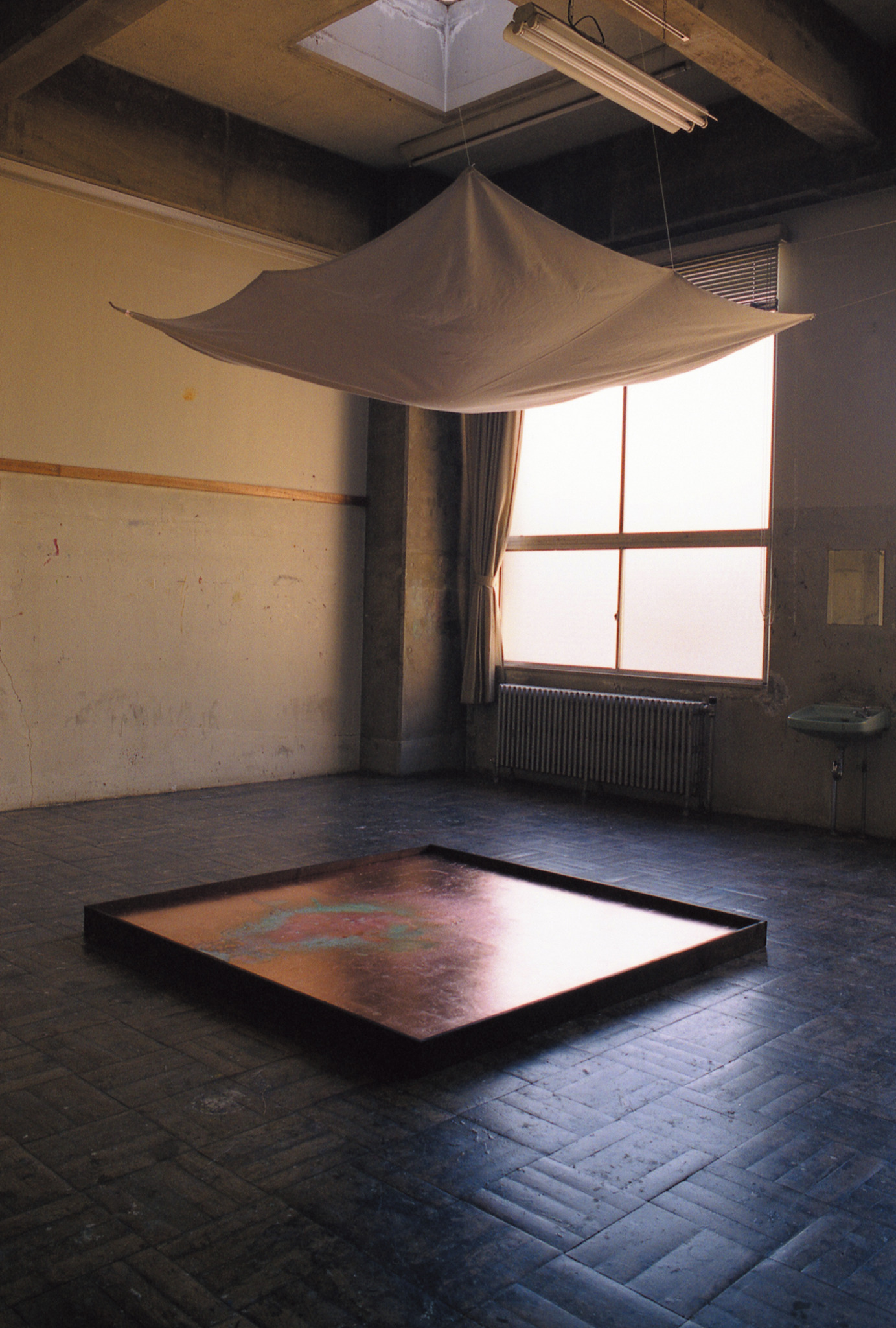 Full installation view of Timbre of Time with suspended cotton cloth above a copper-foil panel
