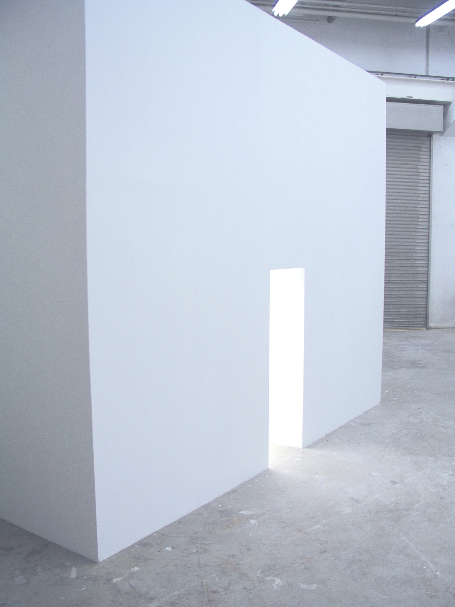 Exterior view of the white cubic booth and narrow illuminated entrance