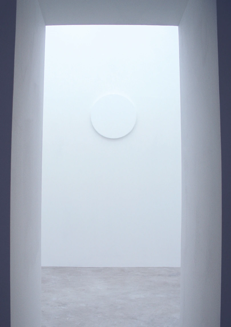 View through the entrance toward the circular white reflective surface